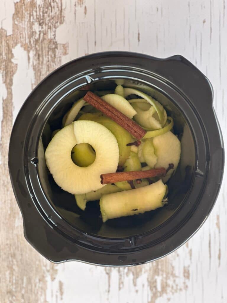A rustic fall simmer pot with floating apple slices, aromatic cinnamon sticks, and cloves, perfect for creating a warm home atmosphere.